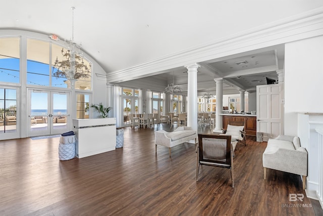 living room featuring dark wood-type flooring, a notable chandelier, french doors, and ornate columns