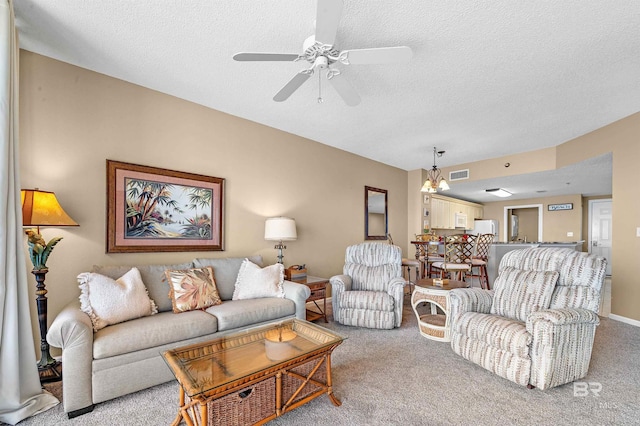 living room featuring a ceiling fan, visible vents, carpet floors, and a textured ceiling