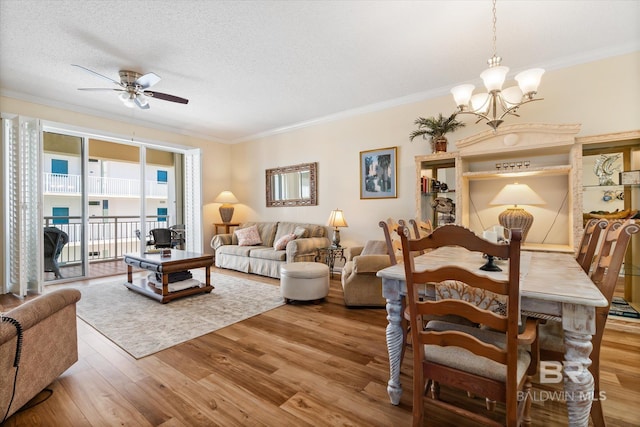 living room with a textured ceiling, ornamental molding, ceiling fan with notable chandelier, and wood finished floors