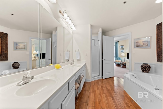 bathroom featuring double vanity, a garden tub, a sink, and wood finished floors