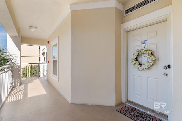 doorway to property featuring a balcony, visible vents, and stucco siding