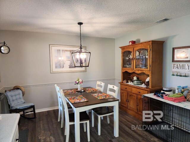 dining room with a textured ceiling, a chandelier, and dark hardwood / wood-style flooring