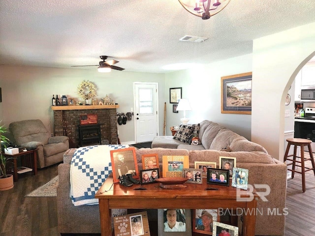 living room featuring ceiling fan, a textured ceiling, and dark hardwood / wood-style floors