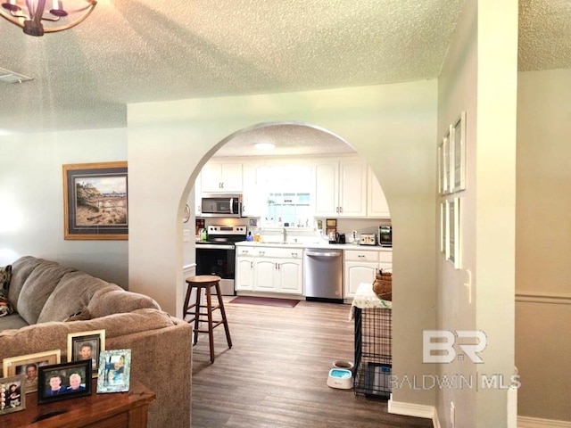 kitchen with stainless steel appliances, light hardwood / wood-style floors, white cabinetry, sink, and a textured ceiling