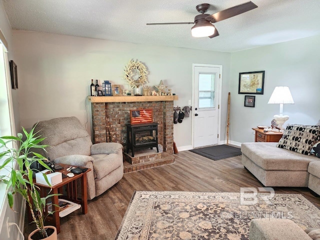 living room with ceiling fan, wood-type flooring, a textured ceiling, and a fireplace