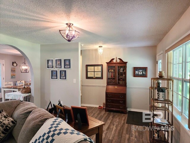 living room featuring a textured ceiling, dark hardwood / wood-style flooring, and an inviting chandelier