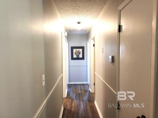 corridor with dark wood-type flooring and a textured ceiling