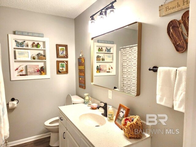 bathroom with a textured ceiling, toilet, and vanity