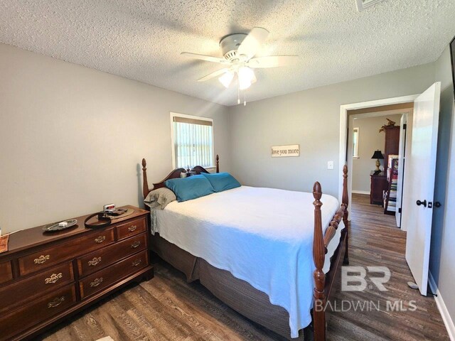 bedroom with a textured ceiling, ceiling fan, and dark hardwood / wood-style floors