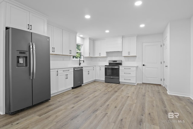 kitchen featuring light countertops, appliances with stainless steel finishes, white cabinets, a sink, and light wood-type flooring