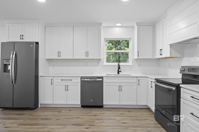 kitchen with white cabinetry, stainless steel appliances, a sink, and light countertops