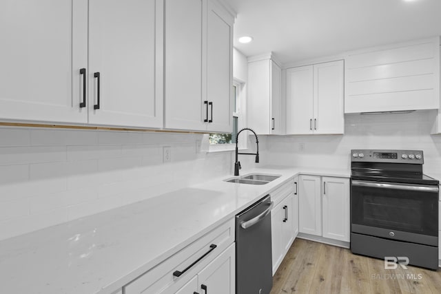 kitchen featuring white cabinetry, appliances with stainless steel finishes, light stone counters, and a sink