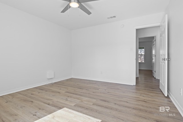 empty room featuring light wood-style flooring, visible vents, ceiling fan, and baseboards