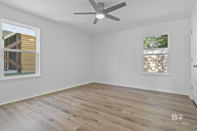 empty room with baseboards, a ceiling fan, and light wood-style floors