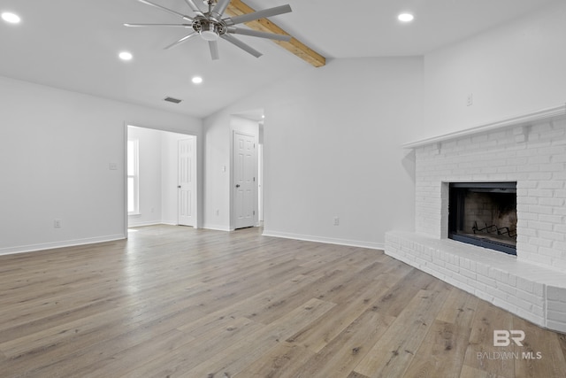 unfurnished living room featuring vaulted ceiling with beams, ceiling fan, baseboards, a brick fireplace, and light wood finished floors