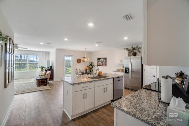 kitchen with appliances with stainless steel finishes, sink, white cabinetry, and an island with sink