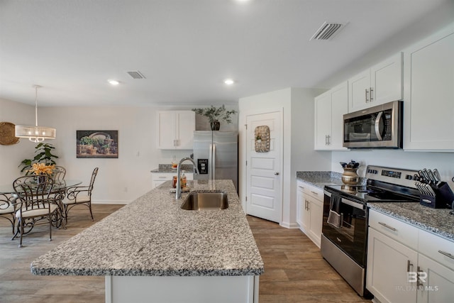 kitchen featuring hardwood / wood-style floors, appliances with stainless steel finishes, sink, and an island with sink