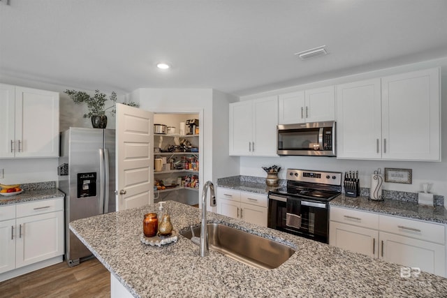 kitchen featuring appliances with stainless steel finishes, white cabinetry, light hardwood / wood-style flooring, and sink