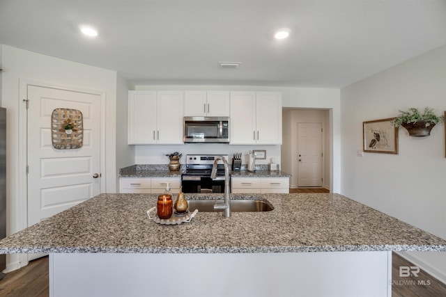 kitchen featuring stainless steel appliances, white cabinetry, dark hardwood / wood-style floors, and an island with sink