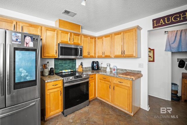 16596 Sugar Loop, Foley, AL 36535 - kitchen featuring a textured ceiling, visible vents, stainless steel appliances, and dark tile patterned flooring