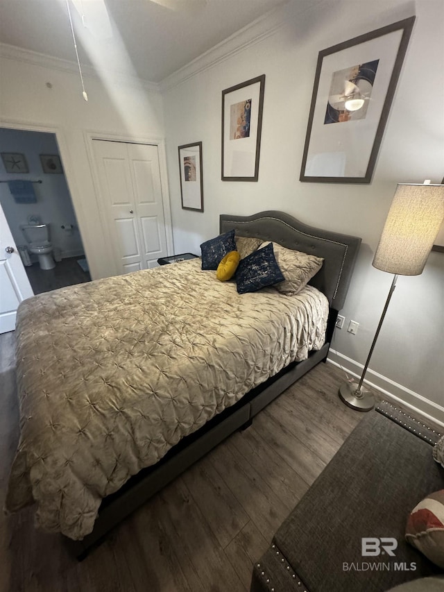 bedroom with wood finished floors, a closet, crown molding, and baseboards