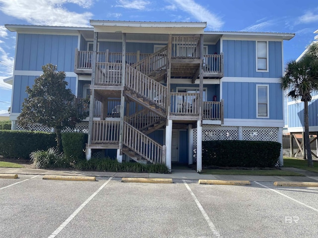 view of building exterior with uncovered parking and stairway