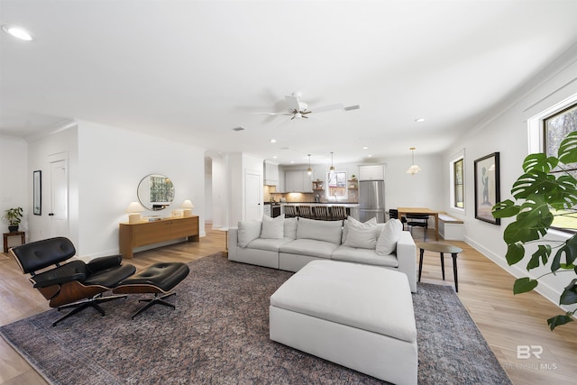 living room with light wood-type flooring, visible vents, baseboards, and recessed lighting