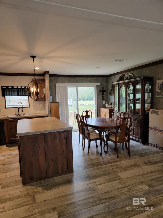 dining room with crown molding, hardwood / wood-style floors, a chandelier, and sink