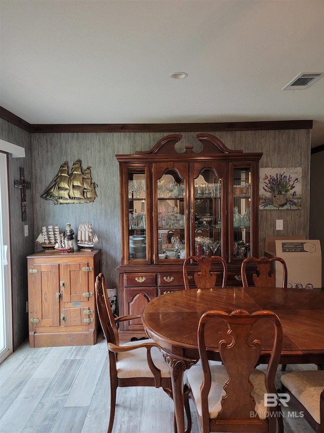 dining space with light wood-type flooring and ornamental molding