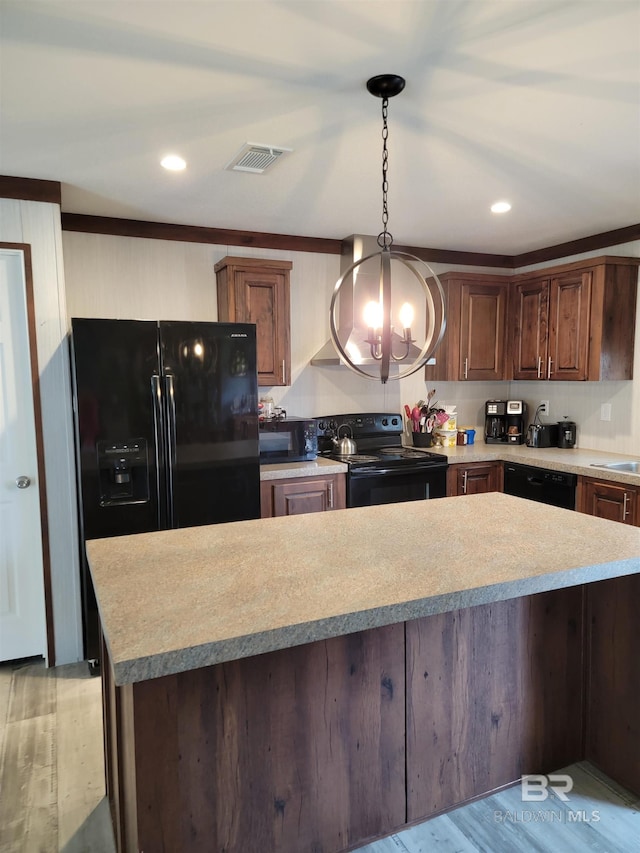 kitchen with pendant lighting, light wood-type flooring, black appliances, and ornamental molding