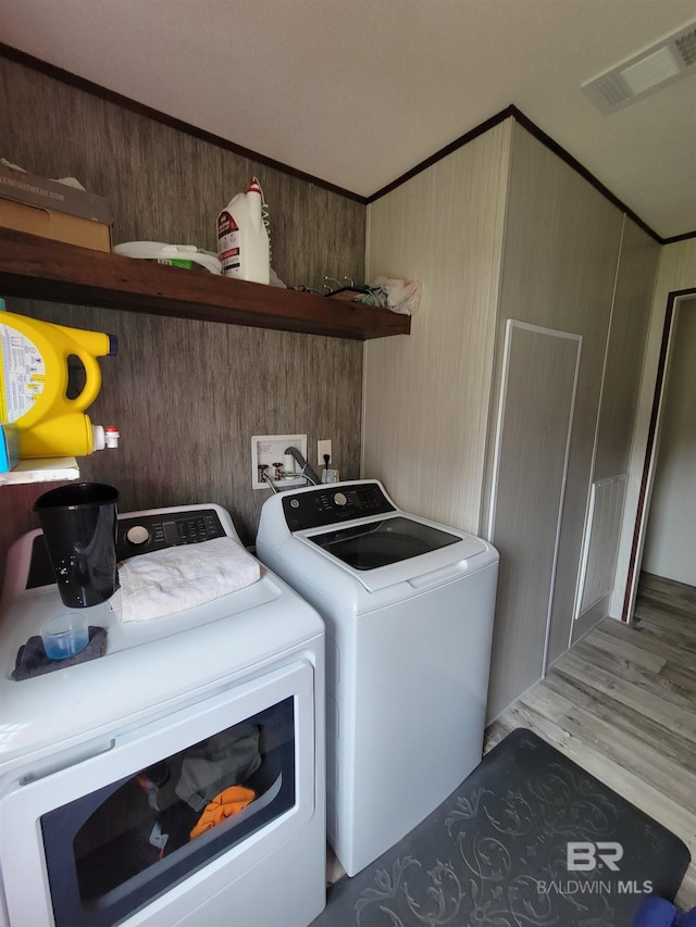 laundry area featuring wood walls, hardwood / wood-style floors, and washer and dryer