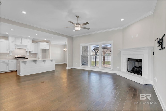 10606 Secretariat Blvd, Daphne, AL 36526 - unfurnished living room with baseboards, ornamental molding, a fireplace, dark wood-type flooring, and ceiling fan with notable chandelier