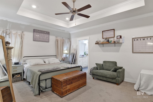 bedroom featuring connected bathroom, ornamental molding, light colored carpet, ceiling fan, and a tray ceiling