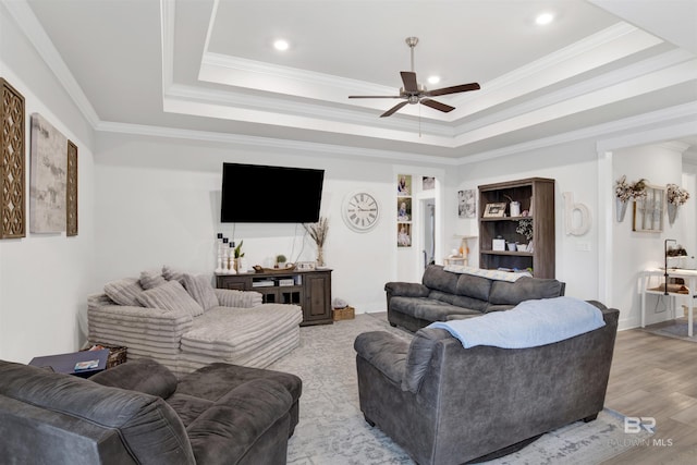 living room featuring crown molding, ceiling fan, light wood-type flooring, and a tray ceiling