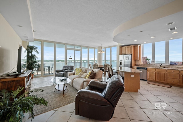 living room featuring expansive windows, a water view, light tile patterned floors, and a healthy amount of sunlight