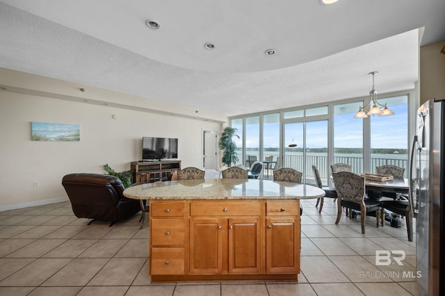 kitchen featuring a wealth of natural light, an inviting chandelier, expansive windows, stainless steel fridge, and pendant lighting