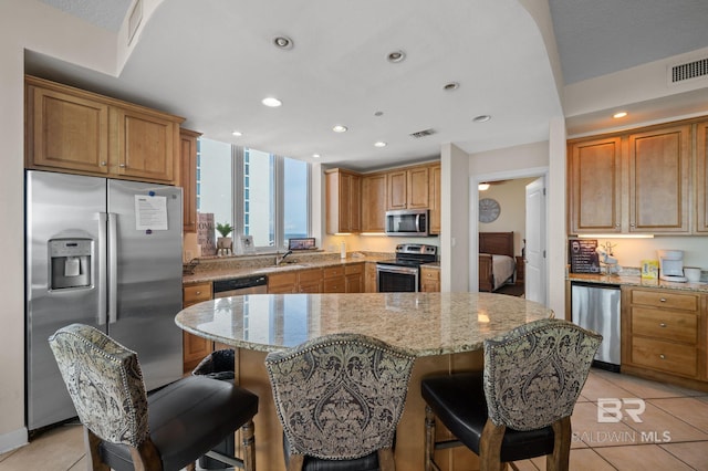 kitchen featuring light stone counters, sink, light tile patterned flooring, and appliances with stainless steel finishes