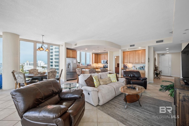 living room with light tile patterned floors, a textured ceiling, and an inviting chandelier