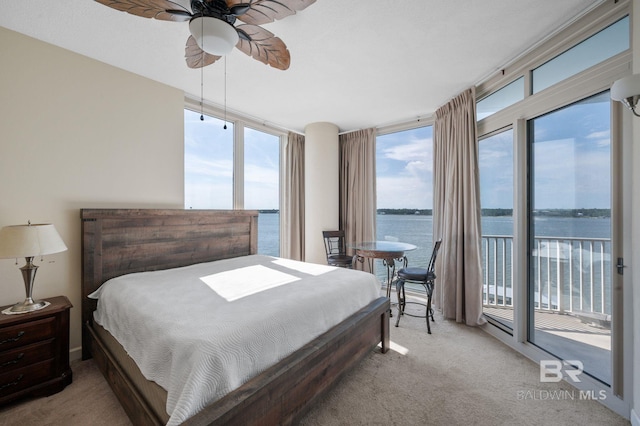 carpeted bedroom featuring access to exterior, a wall of windows, a water view, and ceiling fan