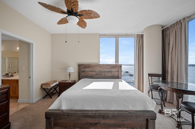 carpeted bedroom featuring expansive windows, a water view, ceiling fan, and ensuite bathroom