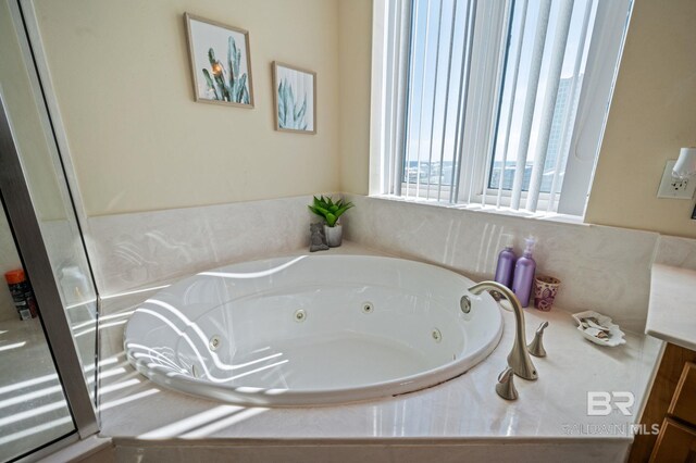 bathroom featuring vanity and a relaxing tiled tub