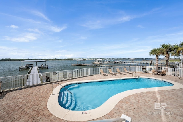 view of pool featuring a water view, a patio, and a boat dock