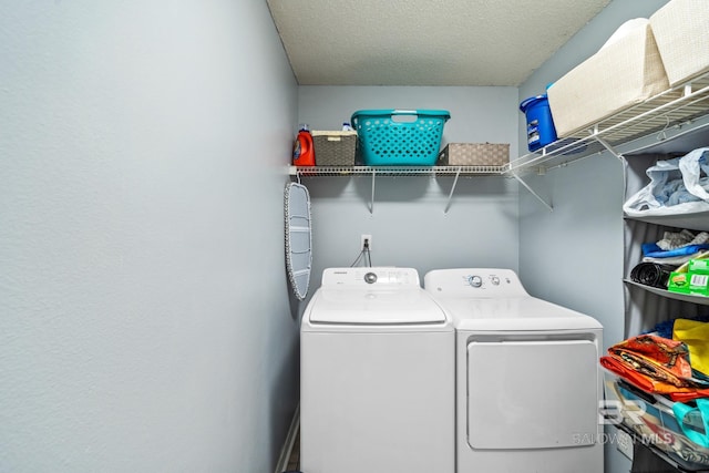 clothes washing area with washing machine and dryer and a textured ceiling