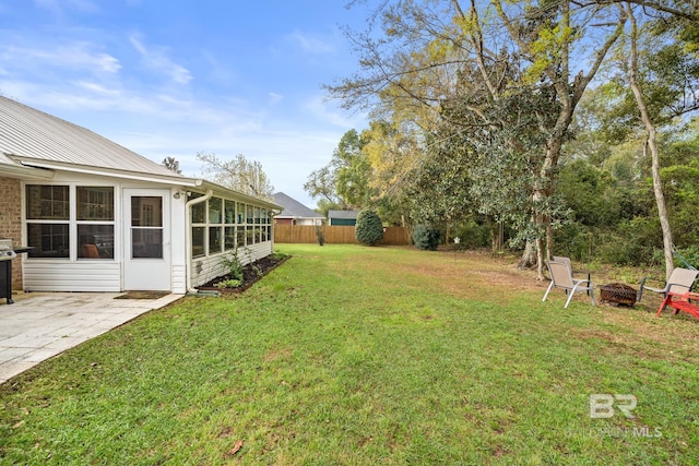 view of yard with a fire pit, a sunroom, and a patio