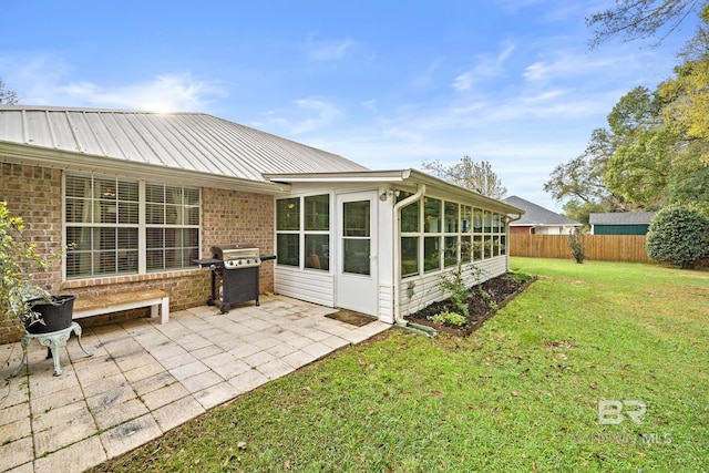 rear view of house with a lawn, a patio area, and a sunroom