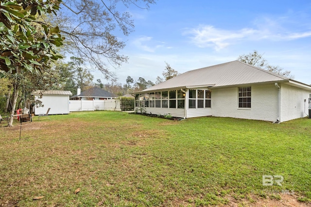 rear view of house with a lawn, a sunroom, and a storage unit