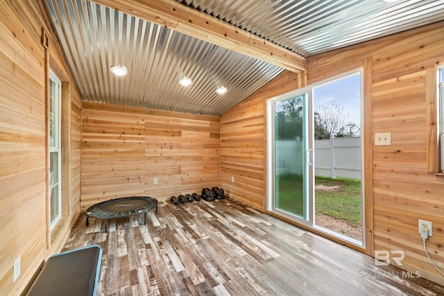 interior space with wood walls, wood-type flooring, and vaulted ceiling