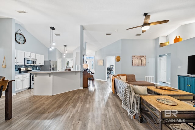 living room featuring ceiling fan, light hardwood / wood-style floors, and high vaulted ceiling