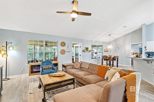 living room featuring ceiling fan, light hardwood / wood-style floors, and lofted ceiling