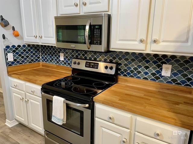 kitchen with wood counters, stainless steel appliances, and white cabinetry